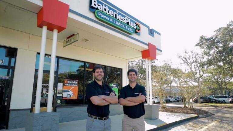 Two franchisees, Javier and Alejandro, are standing in front of a Batteries Plus store.